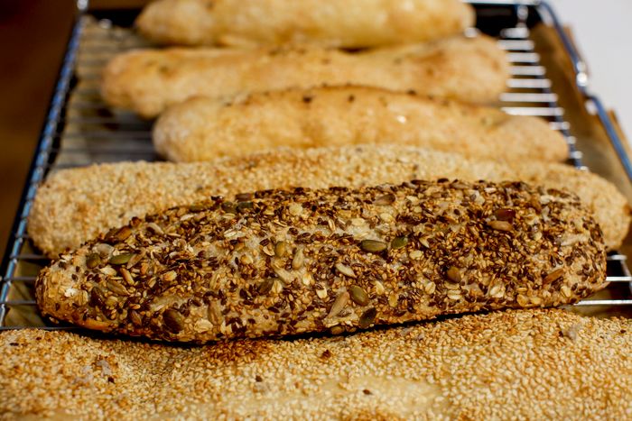 Griglia da forno con diversi filoni di pane allungato, alcuni ricoperti di semi