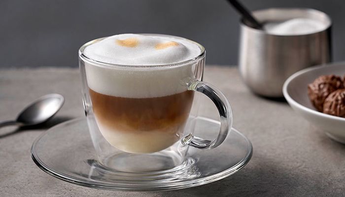 כוס מלאה בקפה על צלוחית ליד כפית