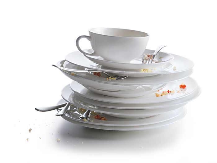 Piatti, tazze e posate impilate con residui di cibo