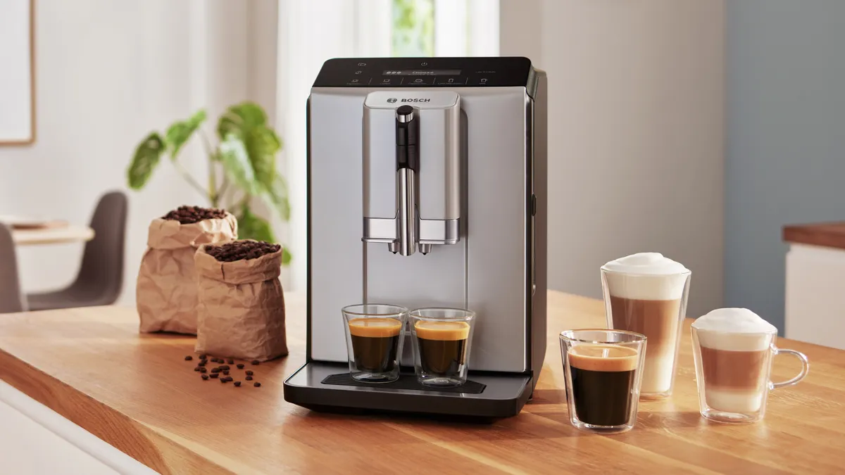 Series 8 VeroCafe fully automatic coffee machine next to 7 cups containing different coffee styles on kitchen top.