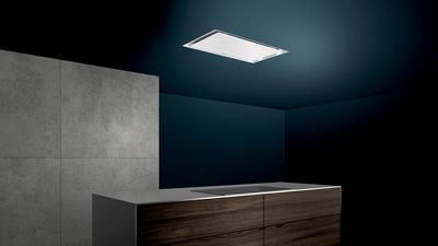 Siemens witte plafondunit verwerkt in een donkerblauwe plafond, boven een kookeiland van beton- en houtlook.