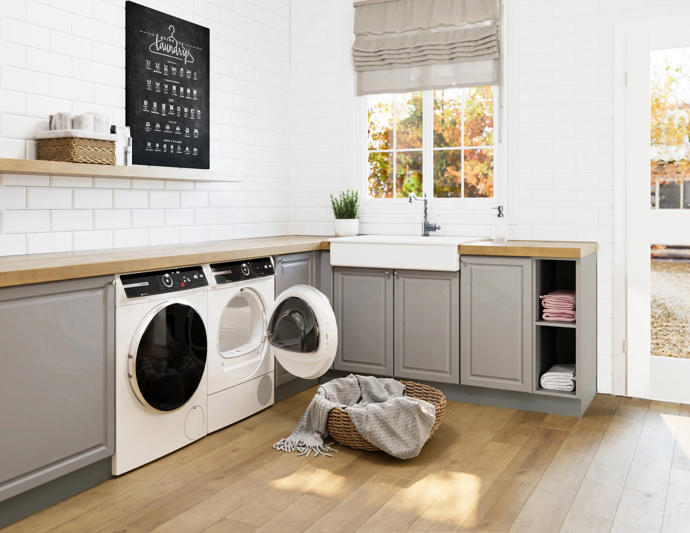 Laundry room with Bosch white washing machine, Bosch white dryer, and sink beside cabinets under large window.