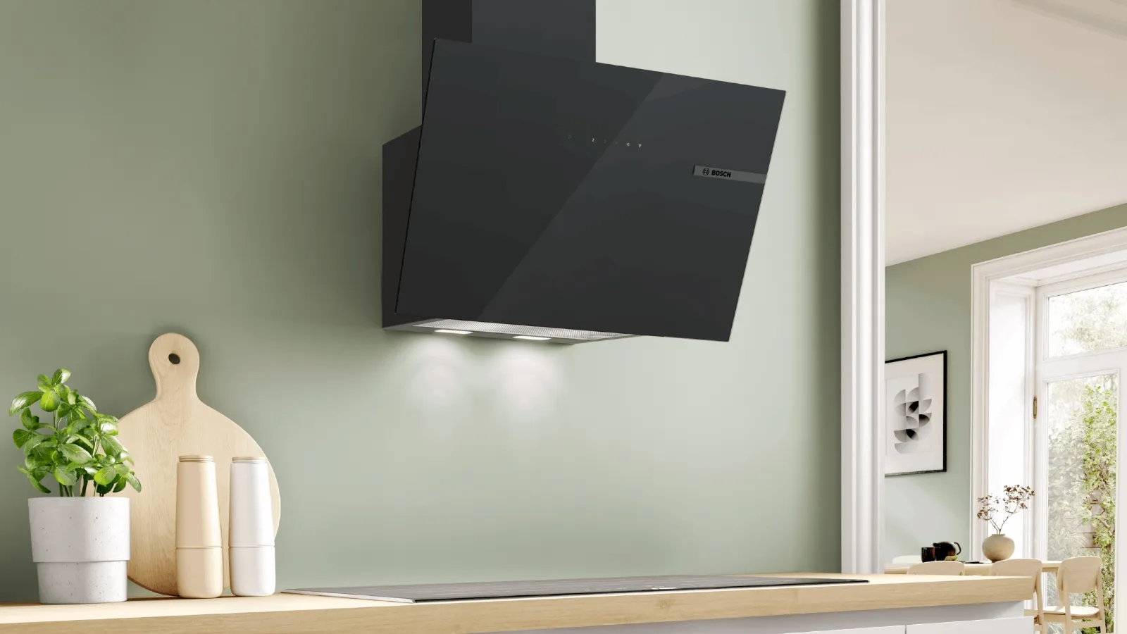 Seinälle asennettu, LED-valoilla varustettu Bosch-liesituuletin vihreässä keittiössä.